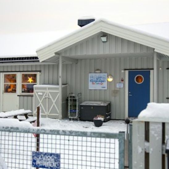 Bilde av barnehagens forside. Viser et snølagt uteområde og et hyggelig inngangsparti.